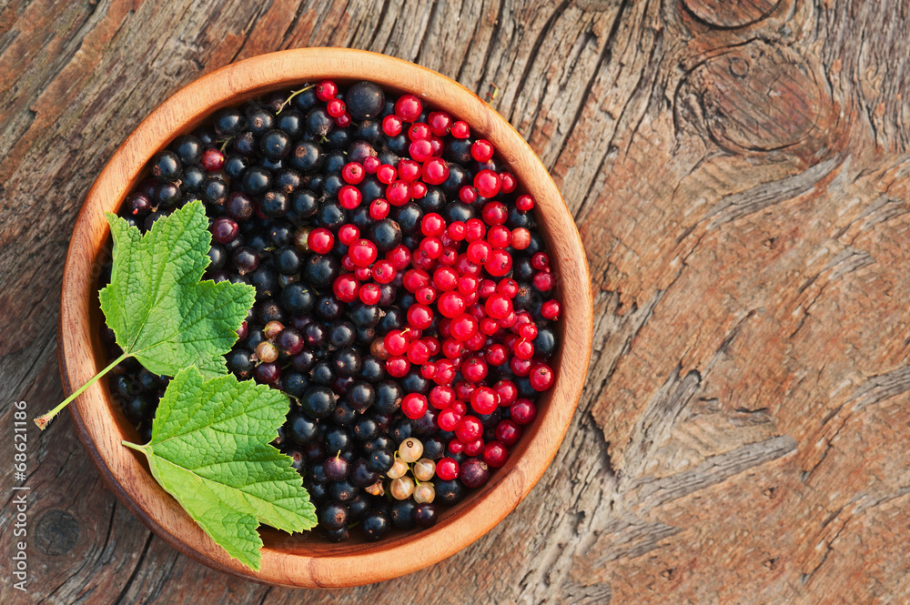 Bllack and red currant and green leaves in wooden bowl. Bllack and red currant and green leaves in wooden bowl.