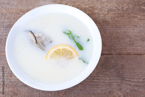 Tasty soup with oysters on wooden table