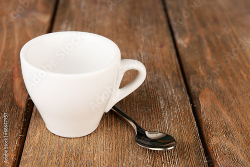 Empty cup with tea spoon on wooden background