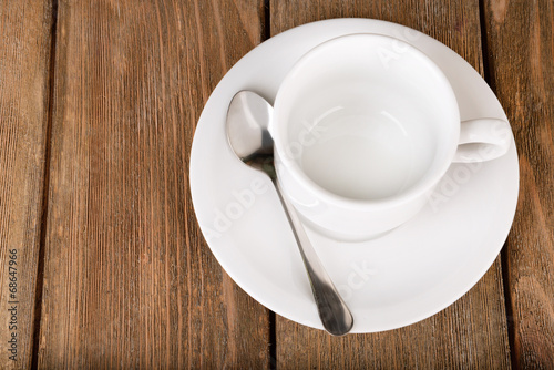 Empty cup with tea spoon on wooden background
