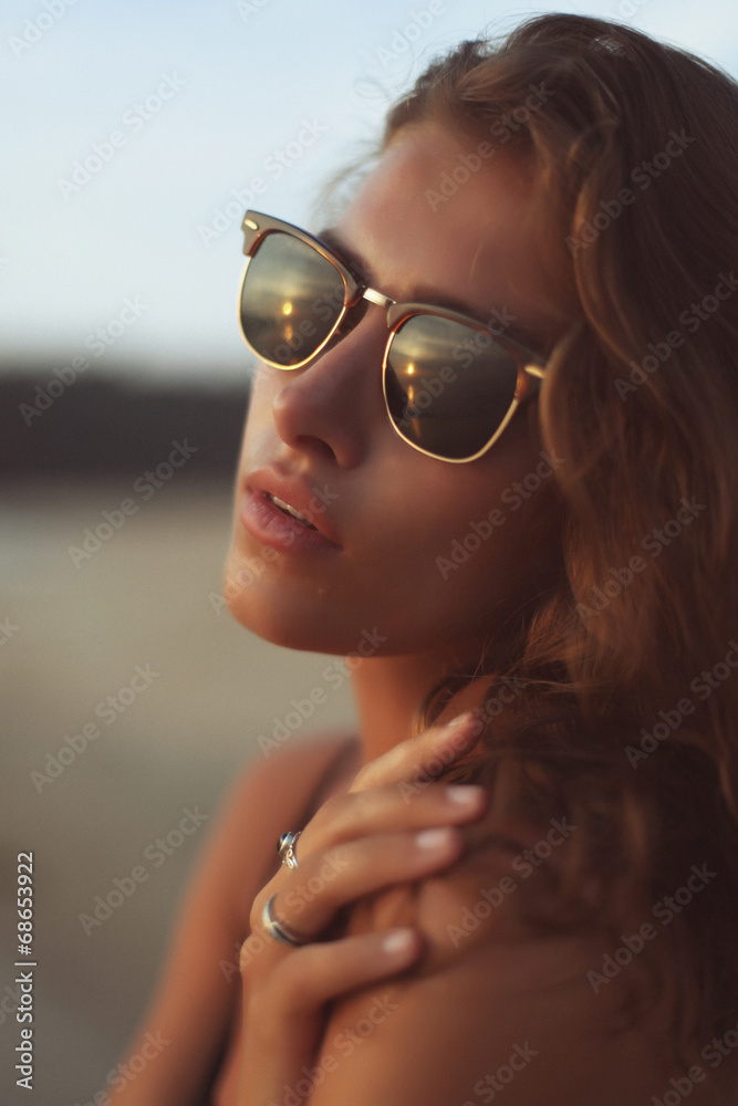 Young beautiful curly woman in sunglasses at the seaside Young beautiful curly woman in sunglasses at the seaside