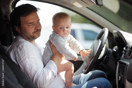 Little baby and his father having fun in a car