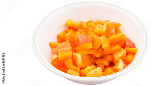 Chopped orange capsicums in white bowls over white background