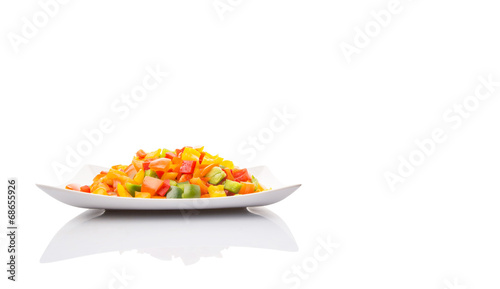 Mix colorful chopped capsicums in a plate over white background photo