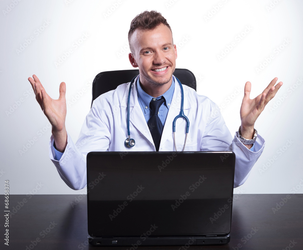 young happy doctor at his desk welcoming you young happy doctor at his desk welcoming you