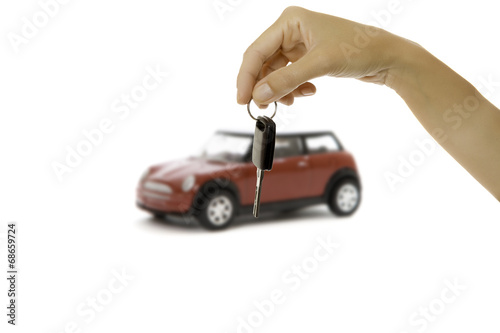 hand holding a key and a car at background