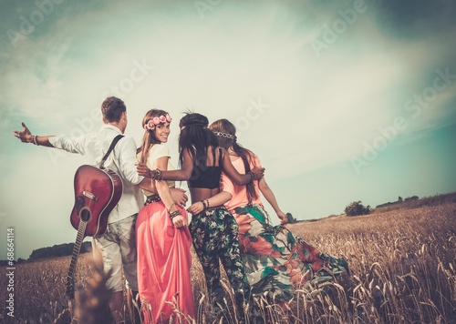 Photo Multi-ethnic hippie friends with guitar in a wheat field