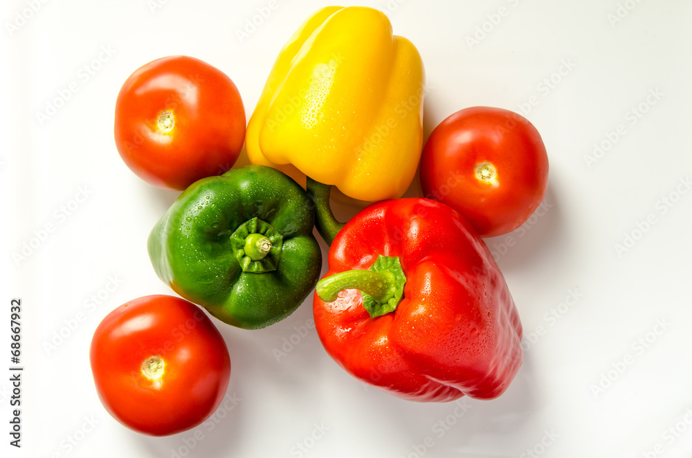 Paprika rot gelb gruen und Tomate nebeneinander auf weiss Paprika rot gelb gruen und Tomate nebeneinander auf weiss