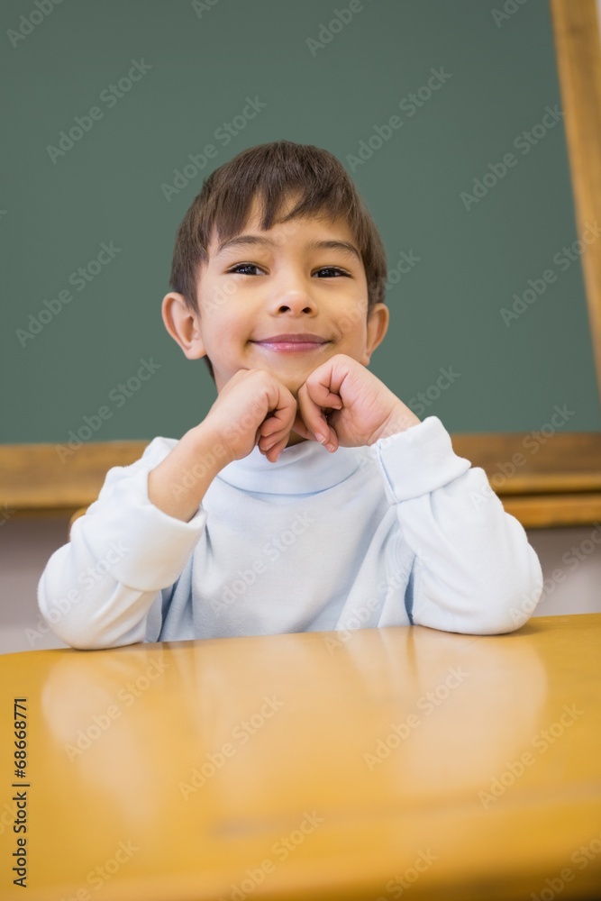 Cute pupil sitting at desk in classroom Cute pupil sitting at desk in classroom