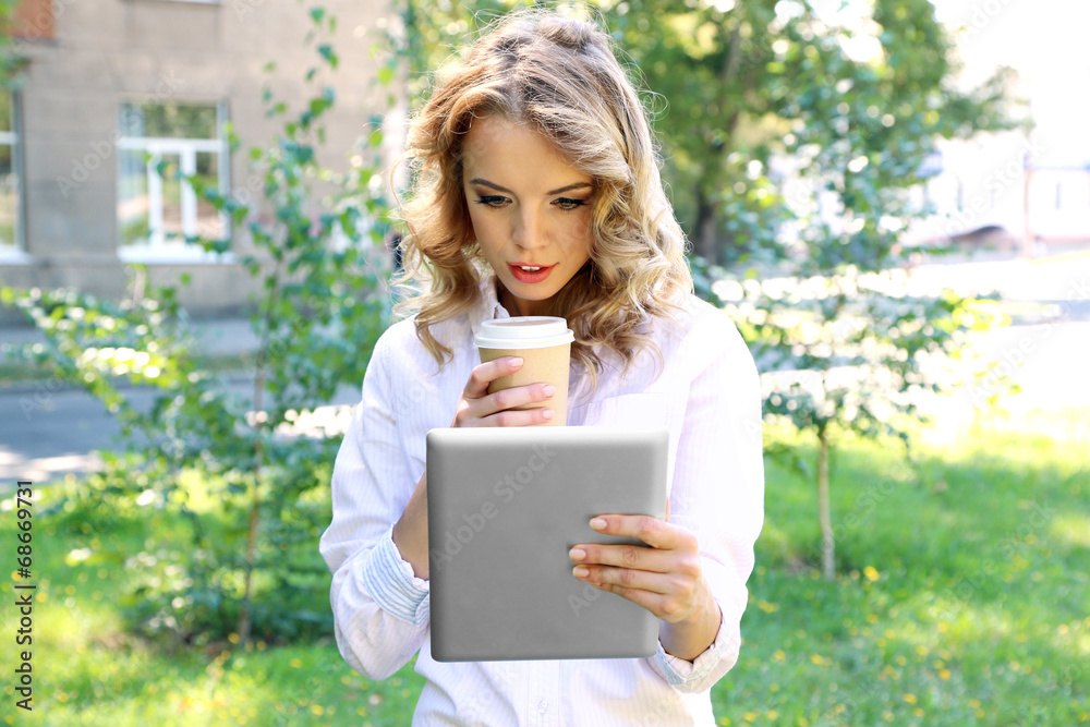 Fototapeta premium Beautiful young girl with tablet on city street