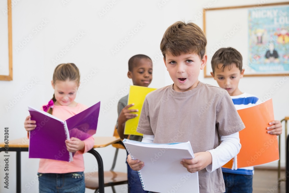 Fototapeta premium Classmates reading from notepads in classroom