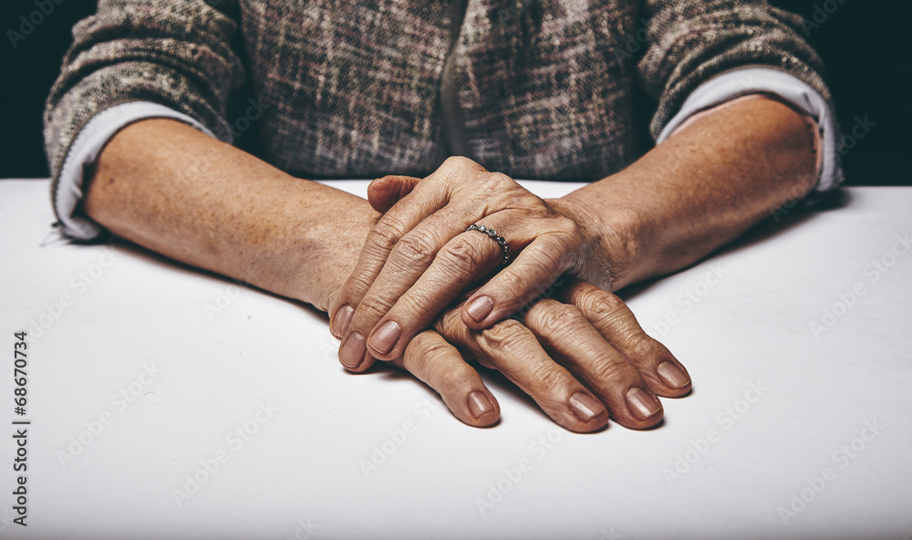 Fototapeta premium Senior woman's hands clasped on a table