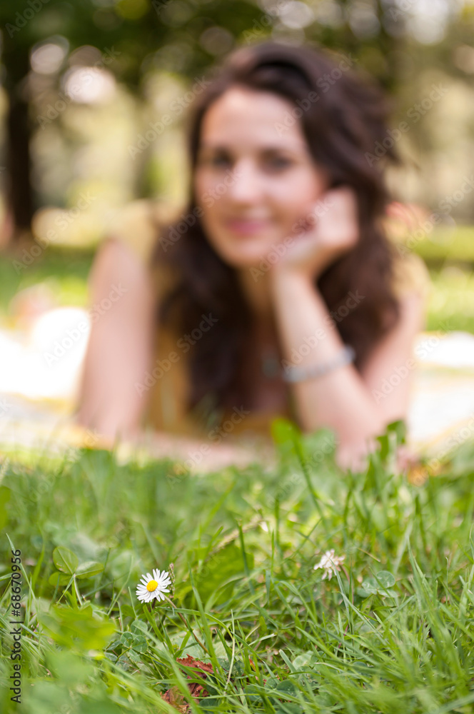 Defocused background with a young woman and a flower on focus at Defocused background with a young woman and a flower on focus at
