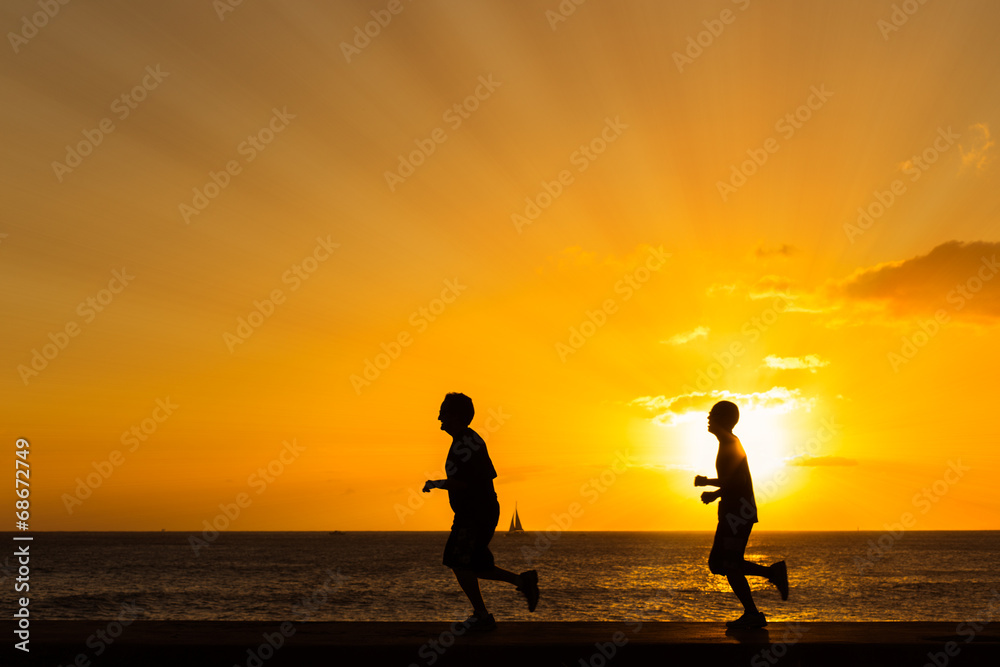 Silhouette of people  jogging at the beach with sunset backgroun