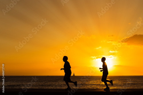 Silhouette of people jogging at the beach with sunset backgroun