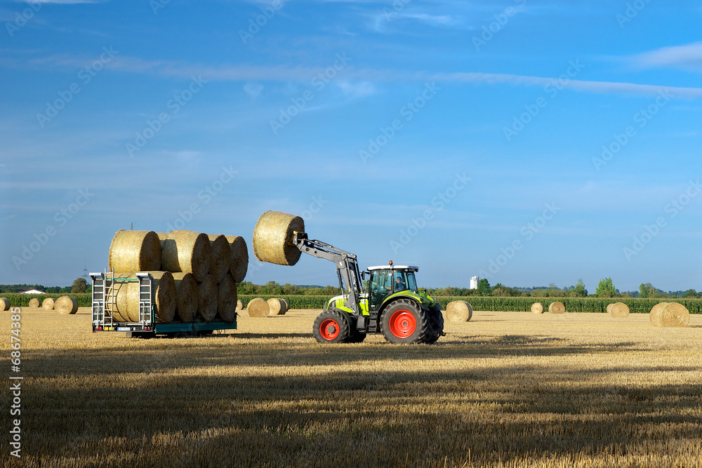 Fototapeta premium Traktor beim aufladen von Strohballen