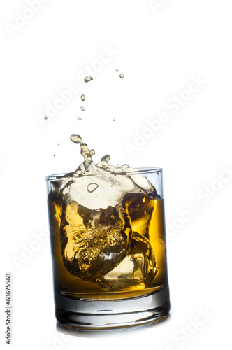 Scotch whiskey splashing out of glass. Isolated on white  backgr