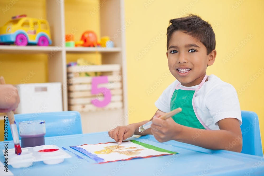 Fototapeta premium Cute little boy painting at table in classroom