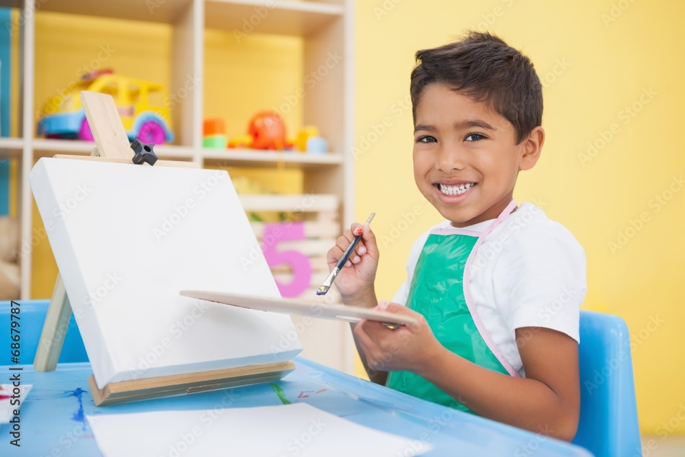 Cute little boy painting at table in classroom Cute little boy painting at table in classroom