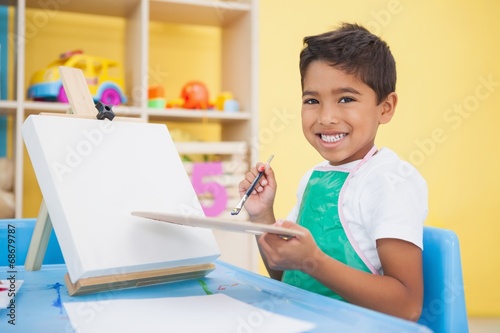 Cute little boy painting at table in classroom