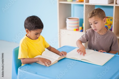 Cute little boys reading at desk in classroom
