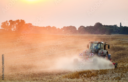 Traktor orzący pole podczas zachodu słońca © Mike Mareen