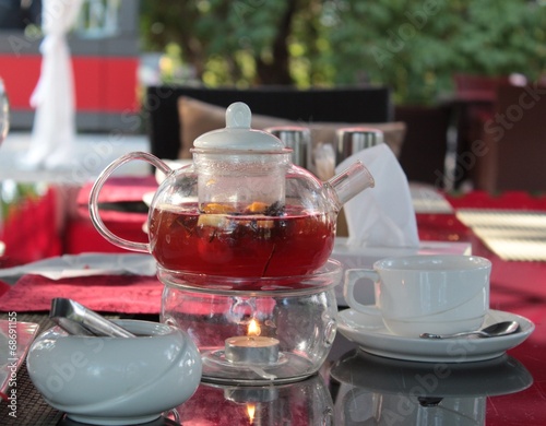 a cup of black tea with teapot in the background. photo