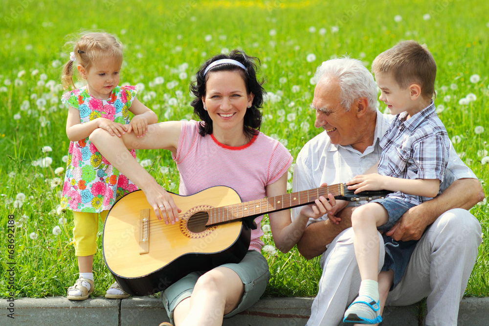 young happy mother playing guitar for her young children 