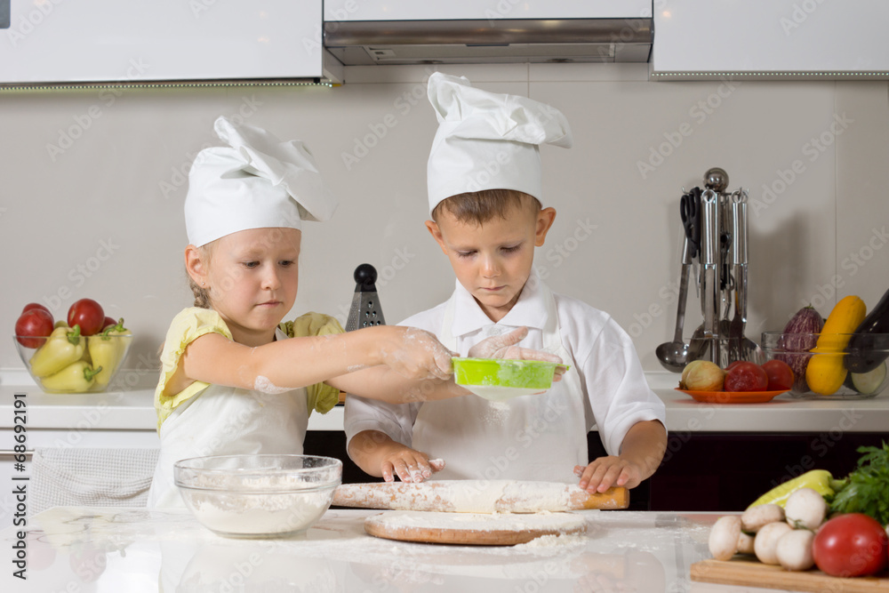 Small boy and girl baking together in the kitchen Small boy and girl baking together in the kitchen