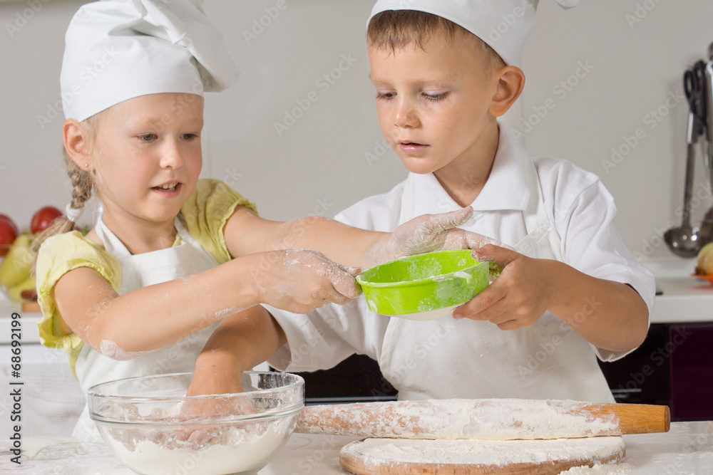 Two children making pastry for pizza bases