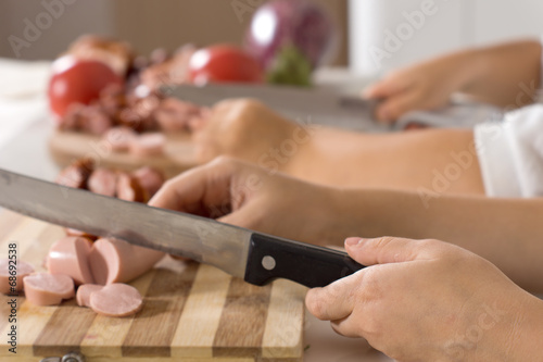 Little boy chopping sausages in the kitchen