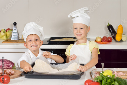 Smiling little cooks preparing a homemade pizza