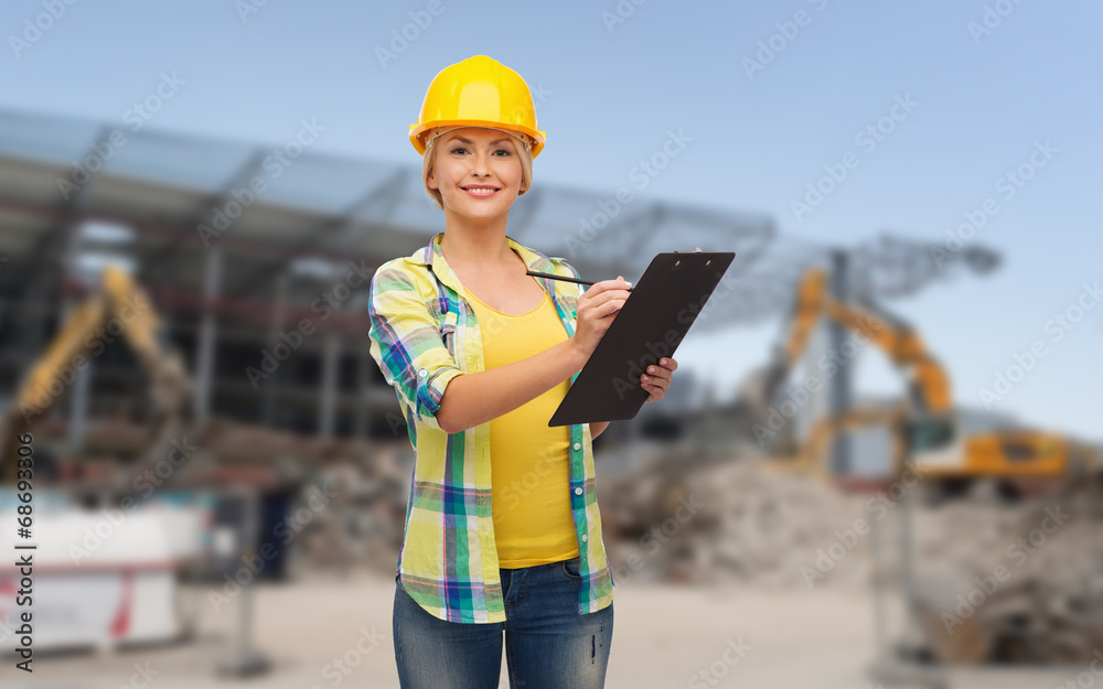 Obraz premium smiling woman in helmet with clipboard