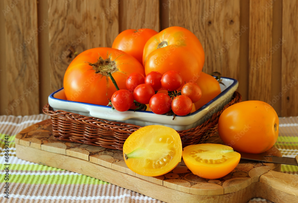 Ripe tomatoes on the plate on the board.