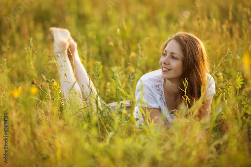 Happy woman lying in a field of grass and flowers