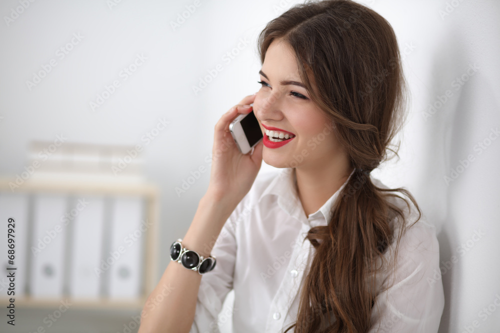Smiling businesswoman talking on phone sitting at the office Smiling businesswoman talking on phone sitting at the office