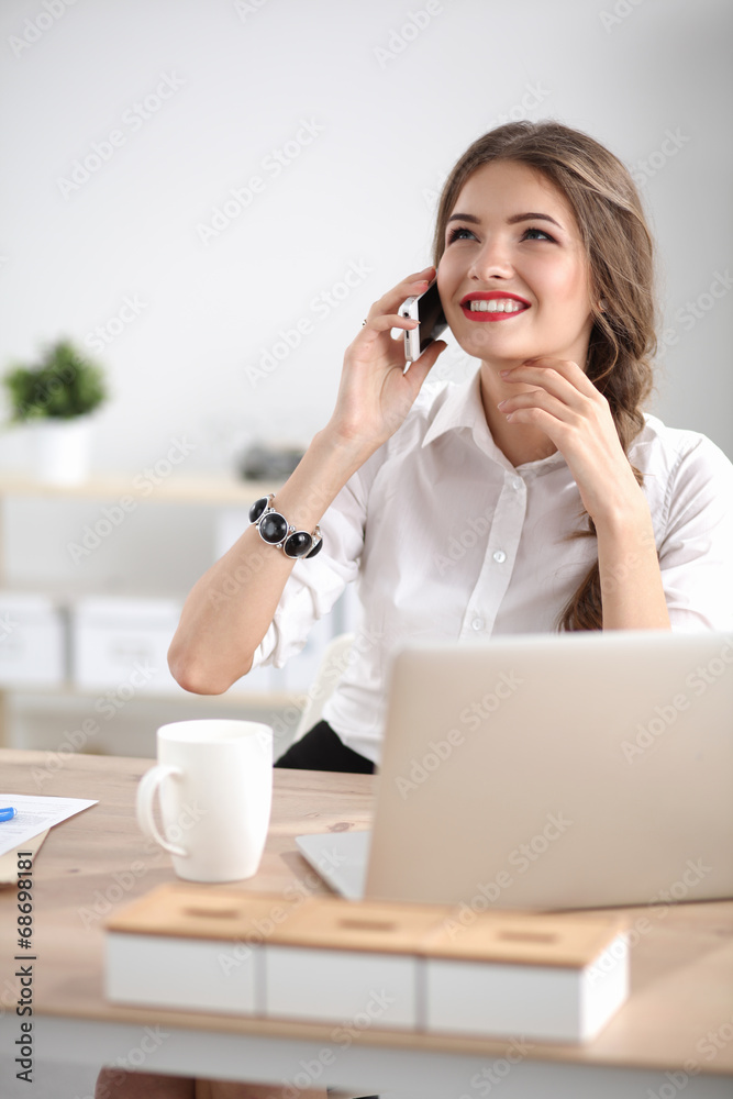 Young businesswoman sitting at the desk and talking on phone Young businesswoman sitting at the desk and talking on phone