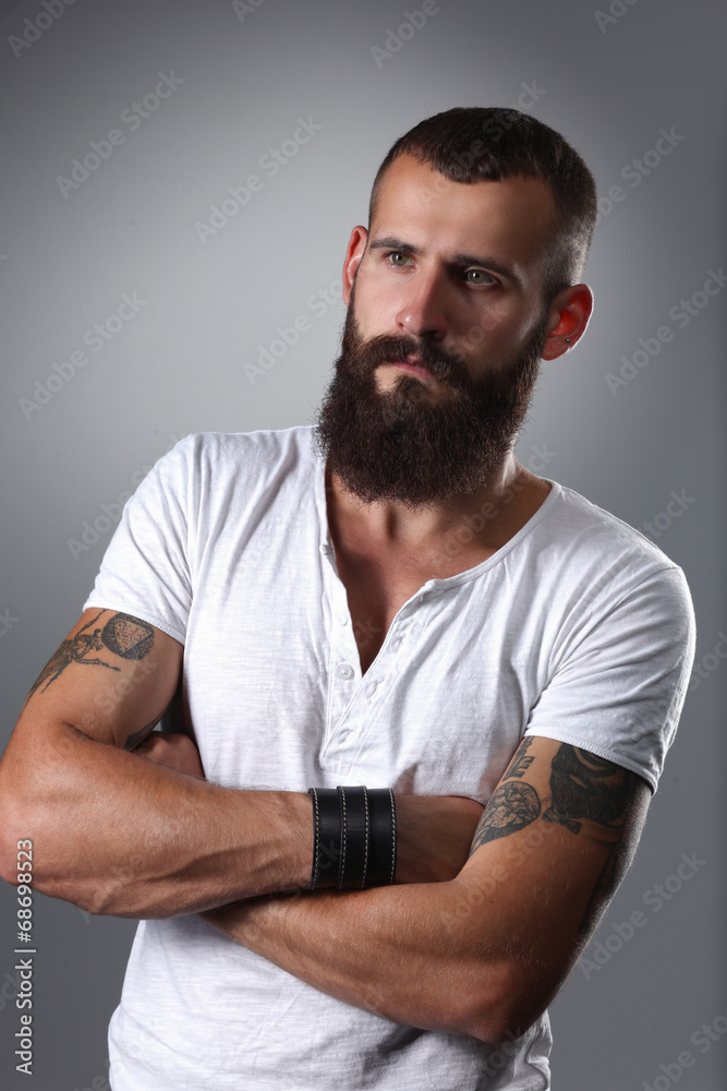 Portrait of handsome bearded man standing with crossed arms,