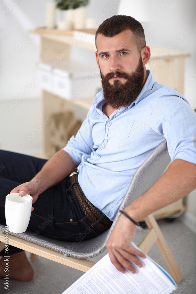 Young man sitting with laptop and a tea cup at home Young man sitting with laptop and a tea cup at home