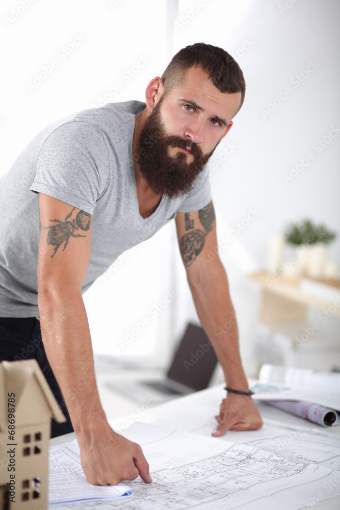 Portrait of male architect with blueprints at desk in office Portrait of male architect with blueprints at desk in office