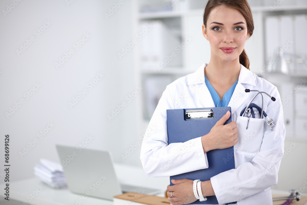 Smiling female doctor with a folder in uniform standing at Smiling female doctor with a folder in uniform standing at