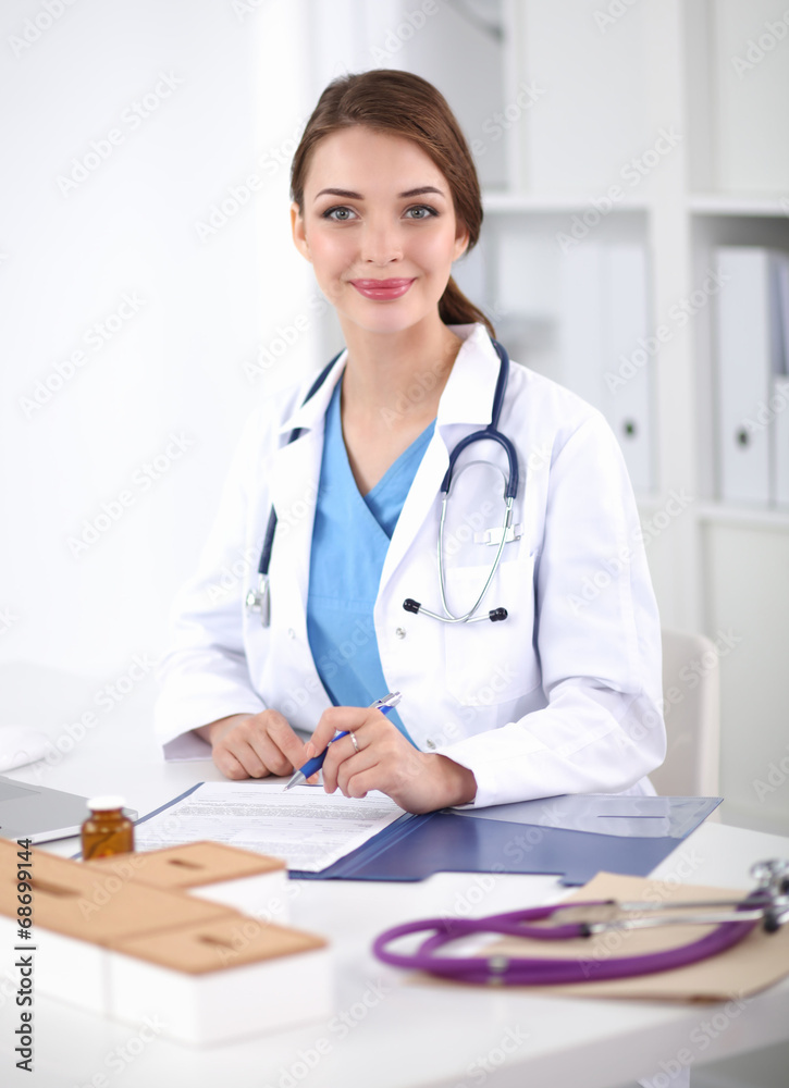Beautiful young smiling female doctor sitting at the desk and Beautiful young smiling female doctor sitting at the desk and