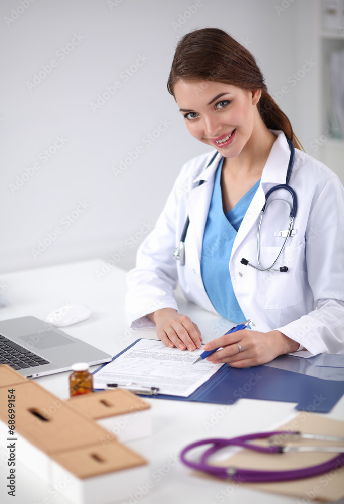 Beautiful young smiling female doctor sitting at the desk and Beautiful young smiling female doctor sitting at the desk and