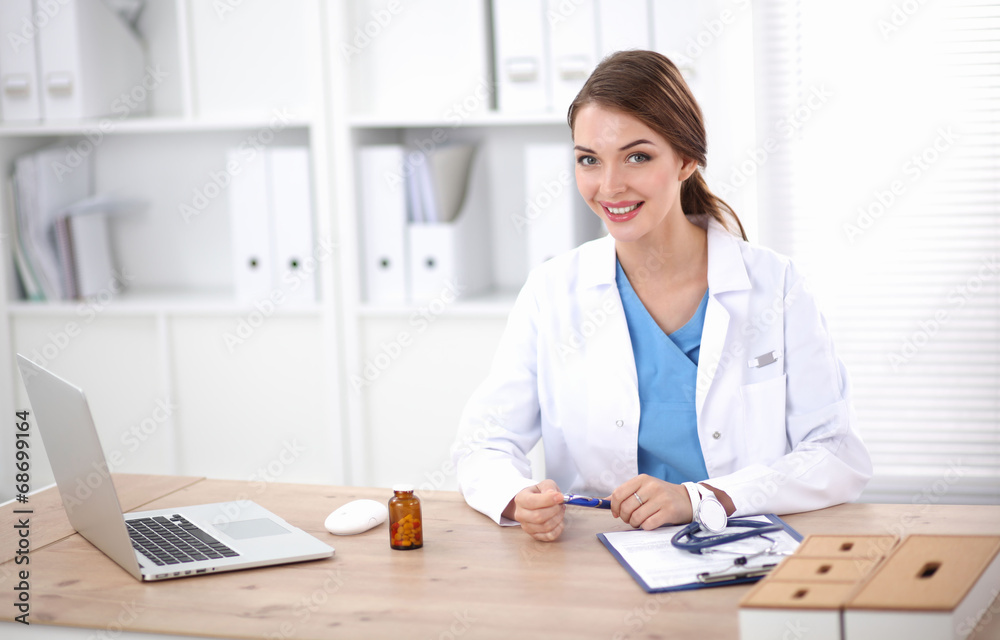 Beautiful young smiling female doctor sitting at the desk and Beautiful young smiling female doctor sitting at the desk and