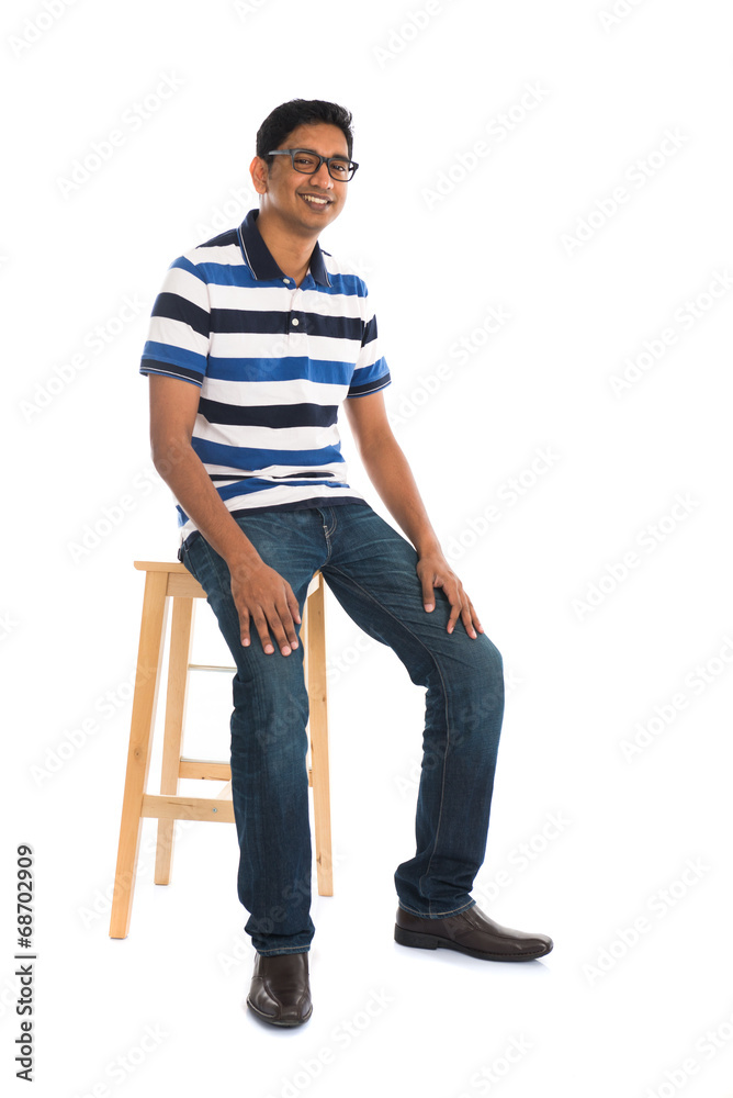 Fototapeta premium Full body indian man sitting on a chair over white background