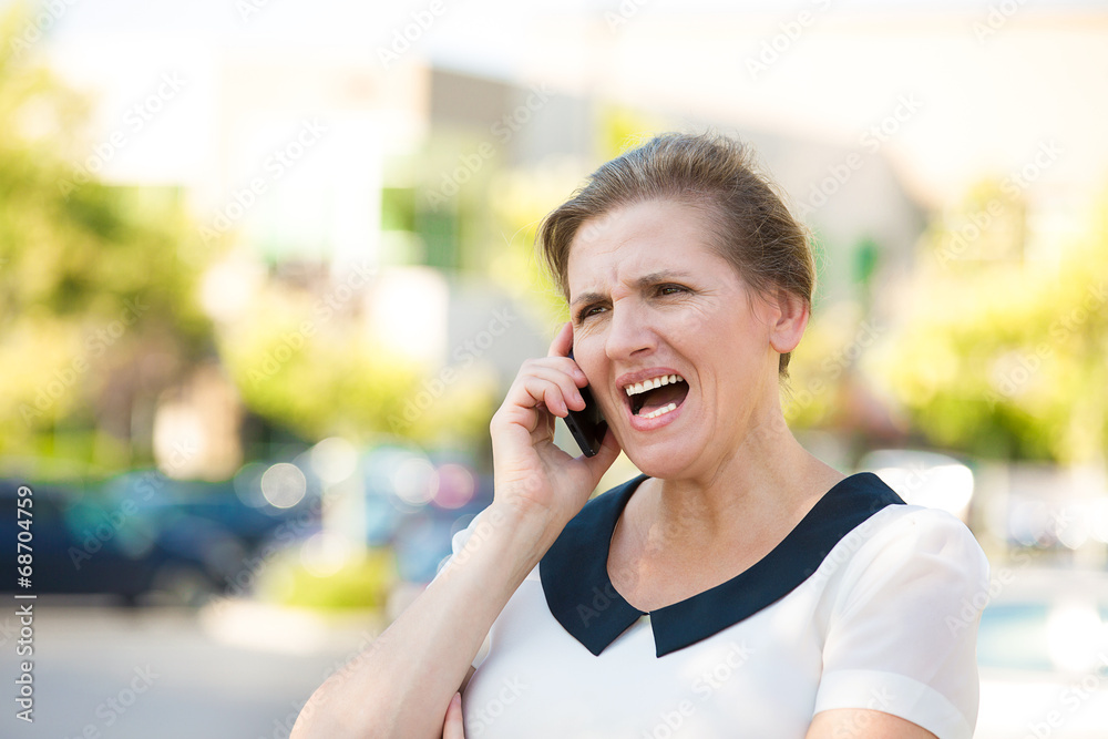 Angry woman screaming on a phone, outside background Angry woman screaming on a phone, outside background