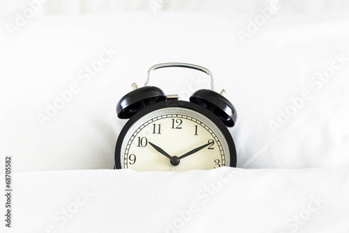 Alarm clock in white blanket
