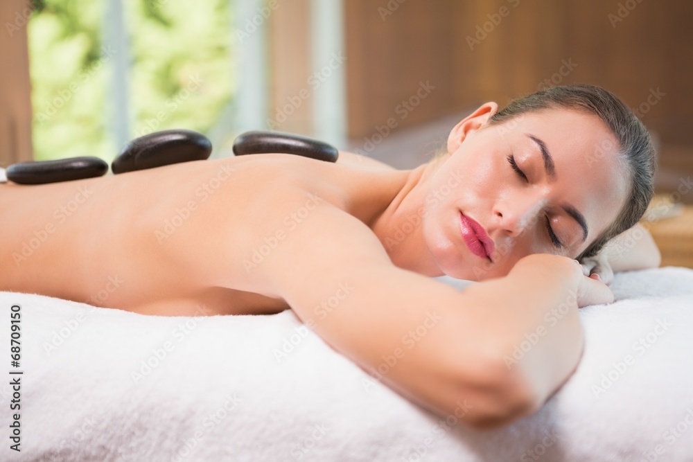 Beautiful woman receiving stone massage at health farm - obrazy, fototapety, plakaty 