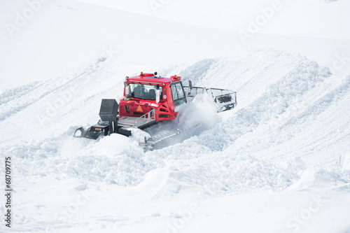 A Tracktor woking on snow field preparing for ski