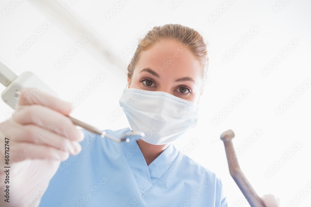 Naklejka premium Dentist in surgical mask holding tools over patient